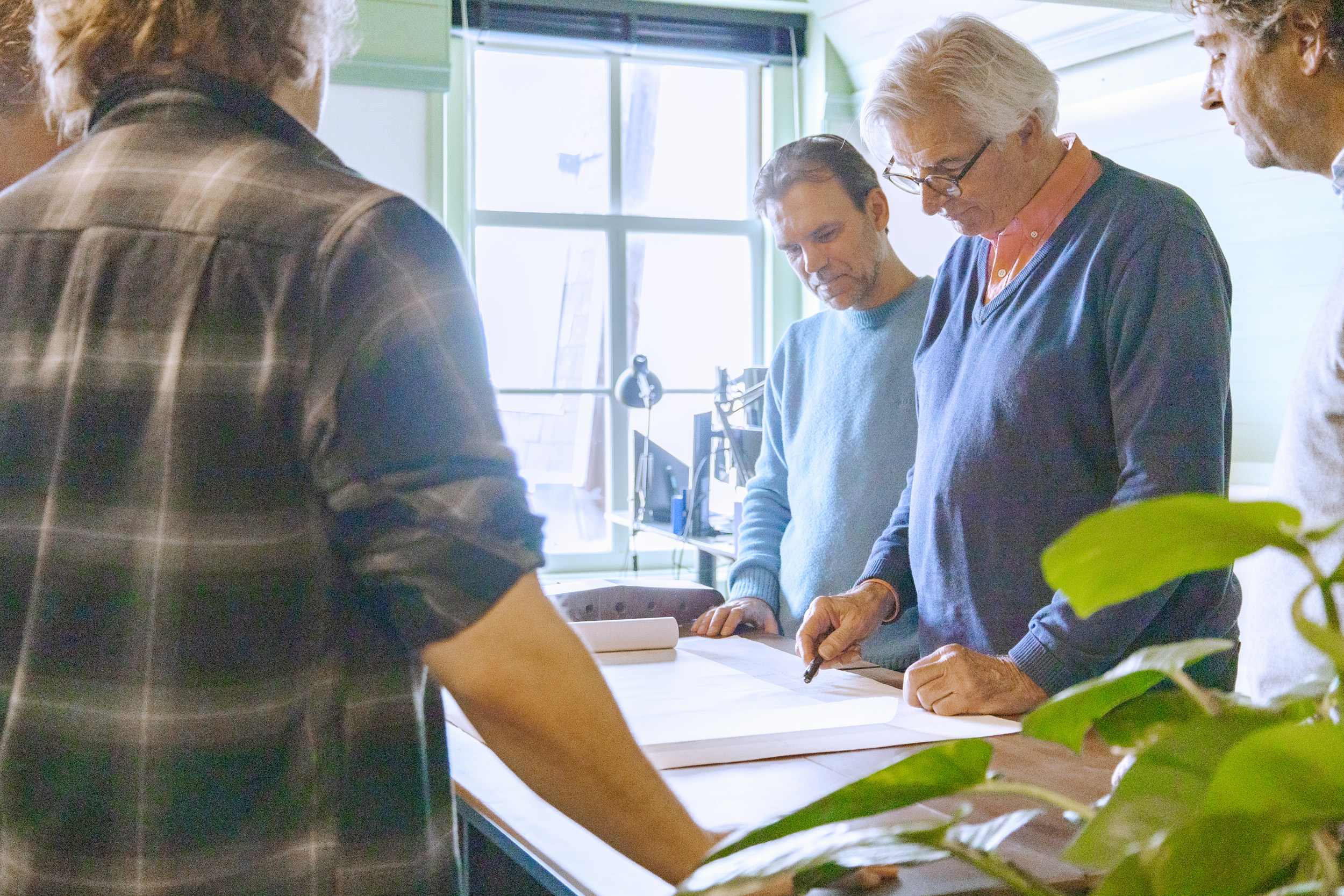 restauratie architecten in overleg over bouwtekeningen op kantoor