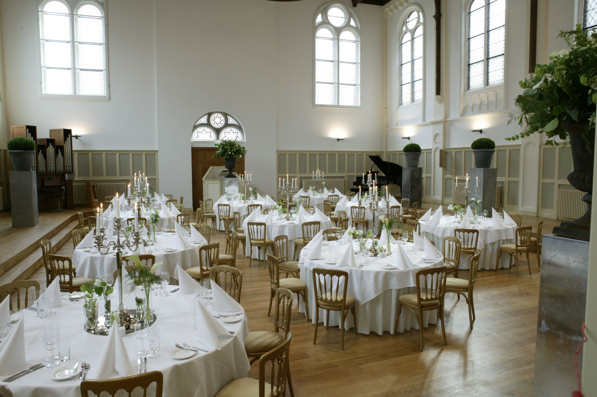 Gerestaureerd interieur van de Paleiskerk in Den Haag met gedekte tafels voor een diner in de hoofdzaal.